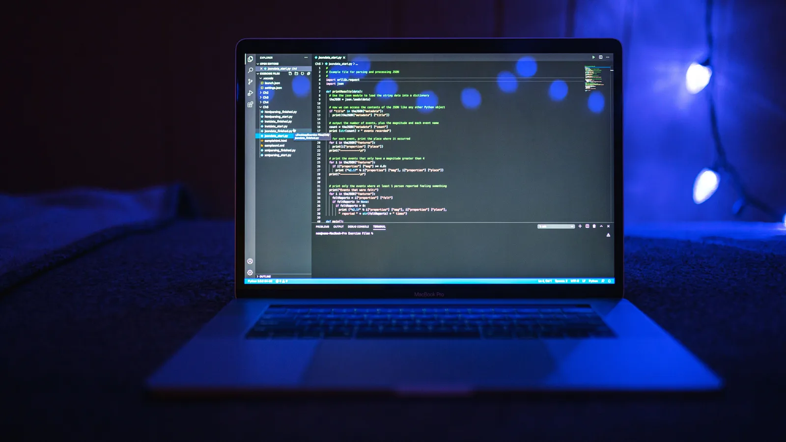 A laptop displaying source code in a dark blue workspace.